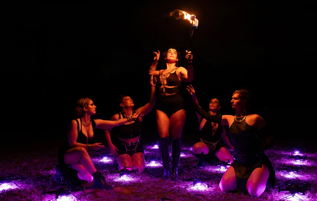 Fire performer with drones in the night sky